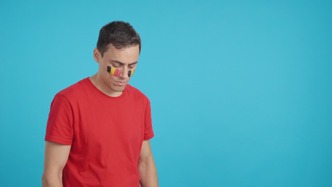 Man with belgian flag painted looking away with serious expression