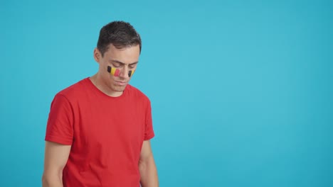 man with belgian flag painted looking away with serious expression