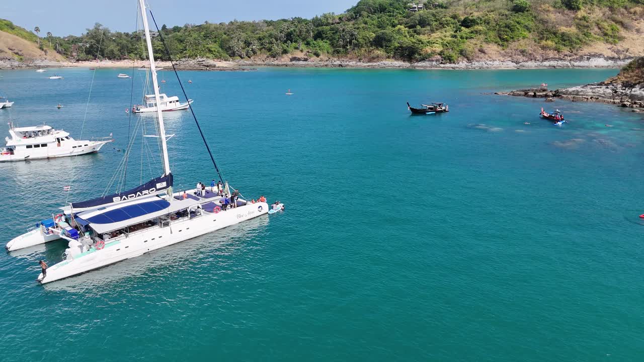 vista aérea de barcos y nadadores en una serena bahía de phuket, que muestra aguas vibrantes de color turquesa y una exuberante costa verde