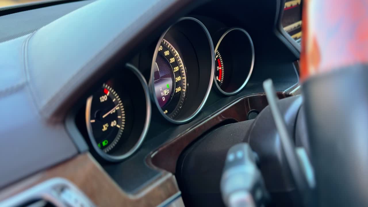 a premium vehicle dashboard featuring an illuminated instrument cluster and wood trim. High-end automotive interior during daylight highlights elegant leather and status design