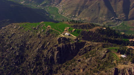 Houses-at-top-of-the-mountain,-beautiful-drone-view,-green-hills-with-living-people,-river-trees-and-forests-at-mountains