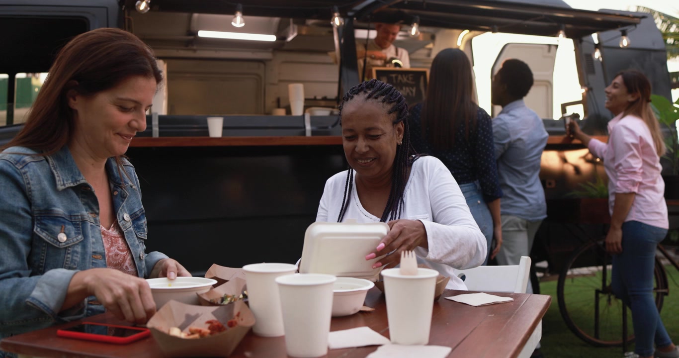 Donne felici di diverse etnie che mangiano a un evento di food truck all'aperto
