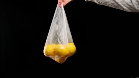 ripe yellow lemons in a transparent plastic bag. woman's hand holds package