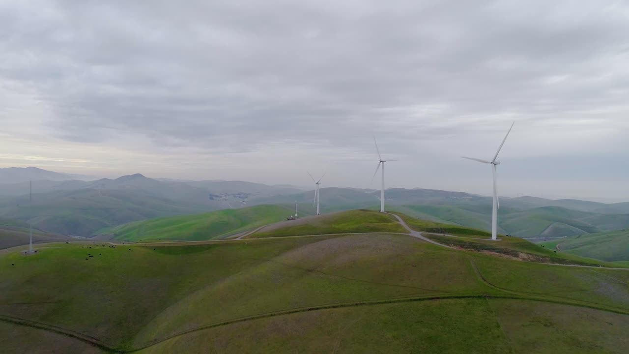Forward Dolly approaching Wind Turbines atop a Hill with Distant Smokey Mountain Mist at Dusk