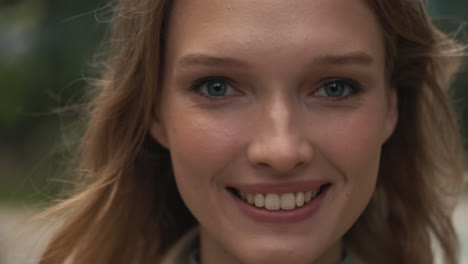 caucasian woman looking at the camera and smiling outdoors.