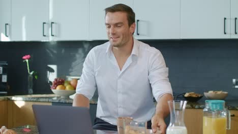 smiling man talking at laptop in luxury kitchen. closeup man having online chat.