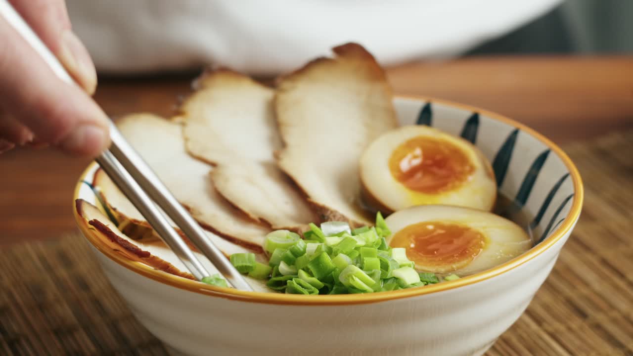 Close-up of ramen bowl with pork, egg, and green onions