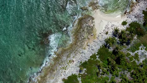 Schöne-Sich-Drehende-Vogelperspektive-Aus-Der-Vogelperspektive-Auf-Einen-Tropischen,-Kargen-Strand-Mit-Klarem-Türkisfarbenem-Wasser,-Weißem-Sand,-Palmen-Und-Wellen,-Die-In-Der-Nähe-Von-Riviera-Maya,-Mexiko,-In-Der-Nähe-Von-Cancun-Gegen-Felsen-Schlagen