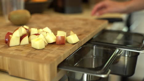 cerca de manos femeninas barriendo cortes de manzana en bin