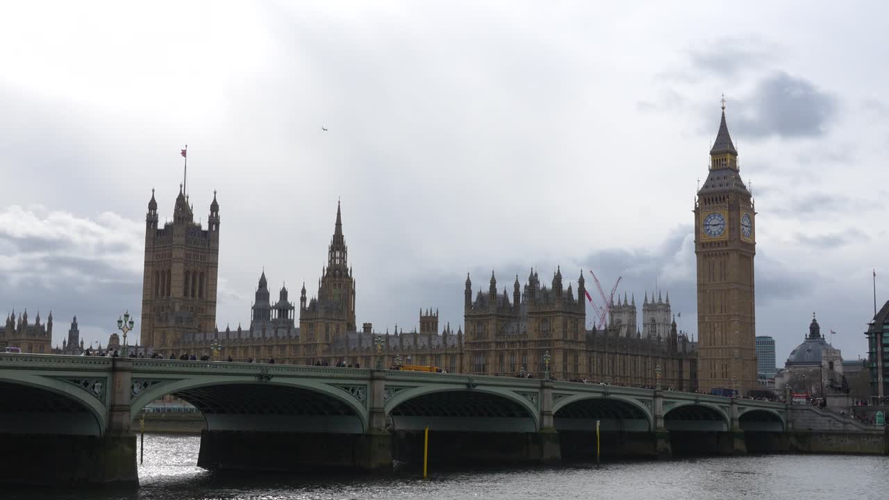 Tháp Big Ben và Tòa nhà Quốc hội ở London cùng với Cầu Westminster bắc qua Sông Thames. Cảnh ban ngày cho thấy giao thông trên cầu, dòng sông và các tòa nhà chính phủ lịch sử.