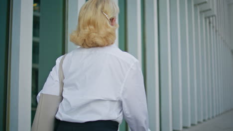 back view pensioner walking at modern city area close up. unknown elderly woman