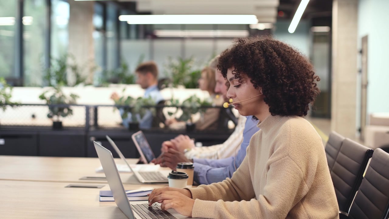 Focused Woman with Headset Typing on Laptop in Modern Office