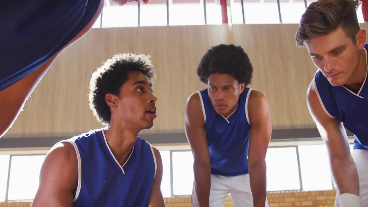 Vielfältiges männliches Basketballteam bespricht im Mannschaftskreis Spieltaktiken.