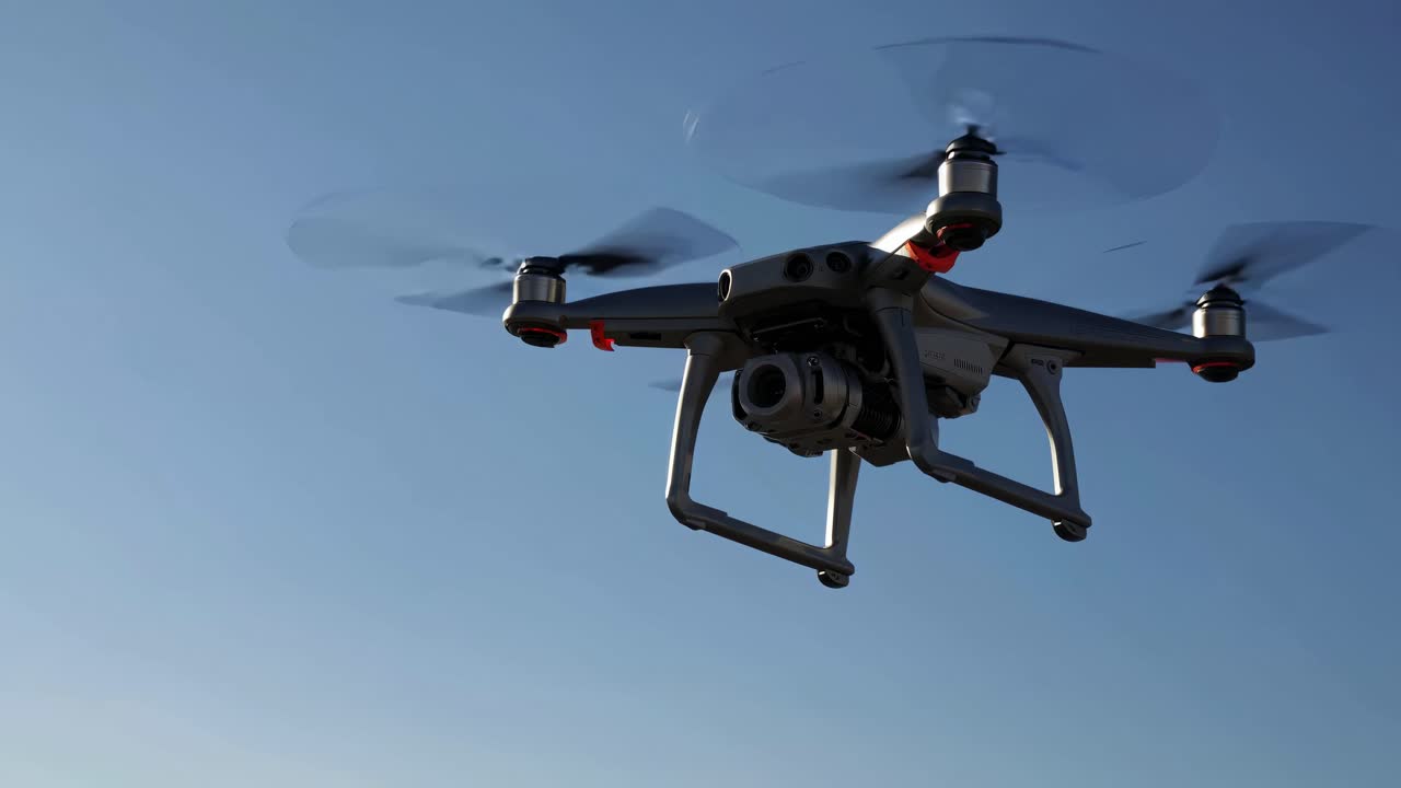 Low-angle shot of a drone in flight against a clear blue sky, capturing video with its camera