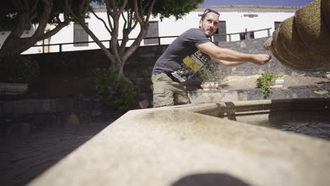 joven viajero aventurero obteniendo agua fresca y fría de una fuente pública en fuerteventura islas canarias españa