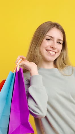 happy customer showing shopping bags on yellow background