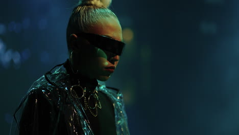 woman with blonde hair wearing sunglasses and a silver jacket performing on stage