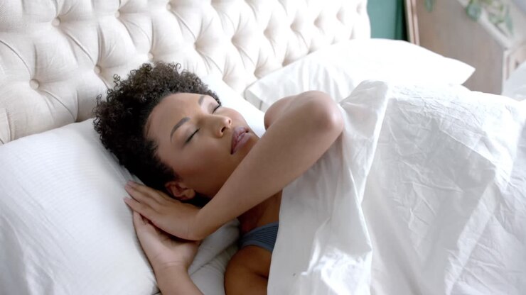 Multietnisk kvinde sover i seng i soveværelse, slowmotion