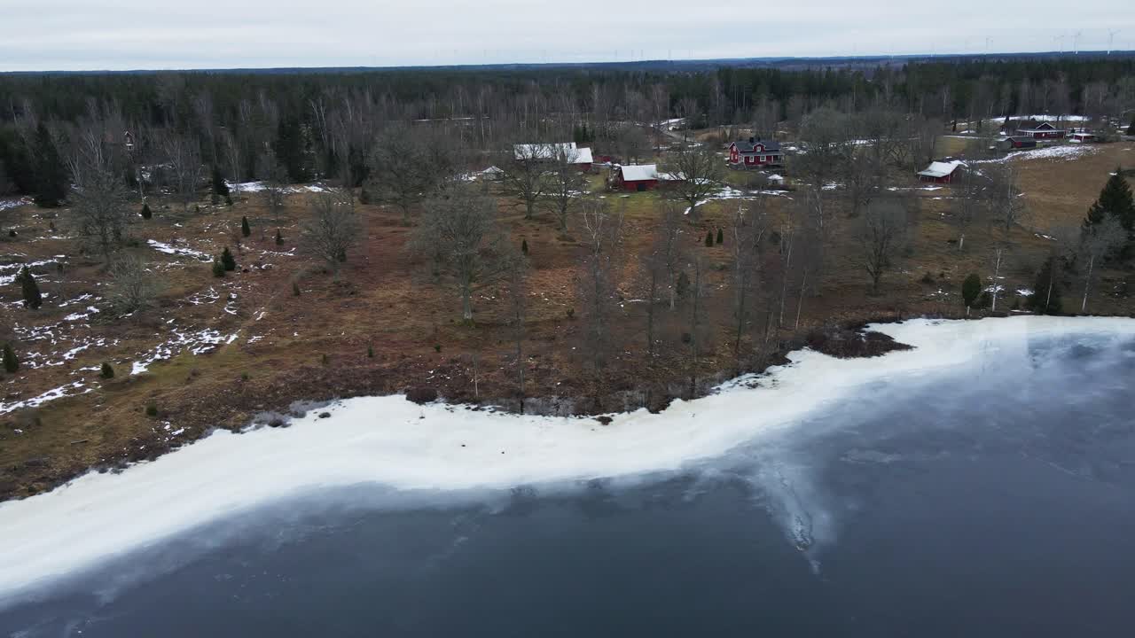 Beautiful aerial of a small town at the edge of a frozen lake in rural Sweden
