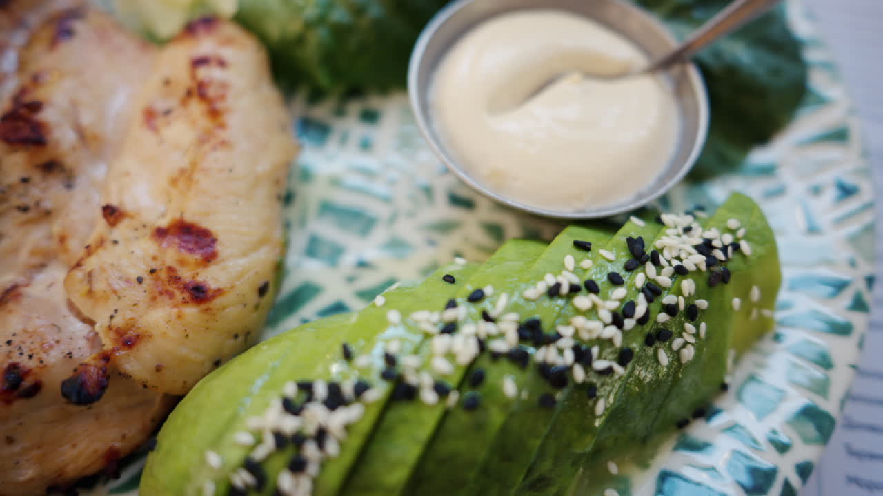 Close up of a piece of a cooked chicken tender with avocado and sauce