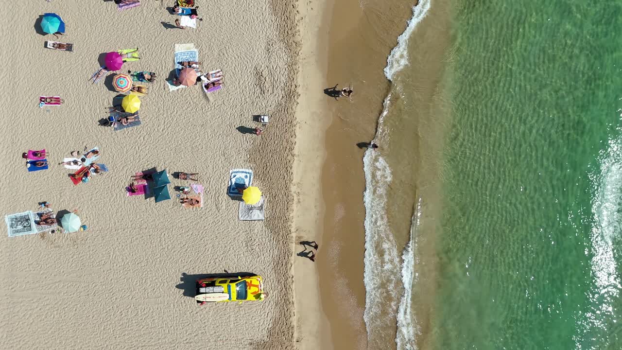 Aerial view of a beach with people and a lifeguard truck