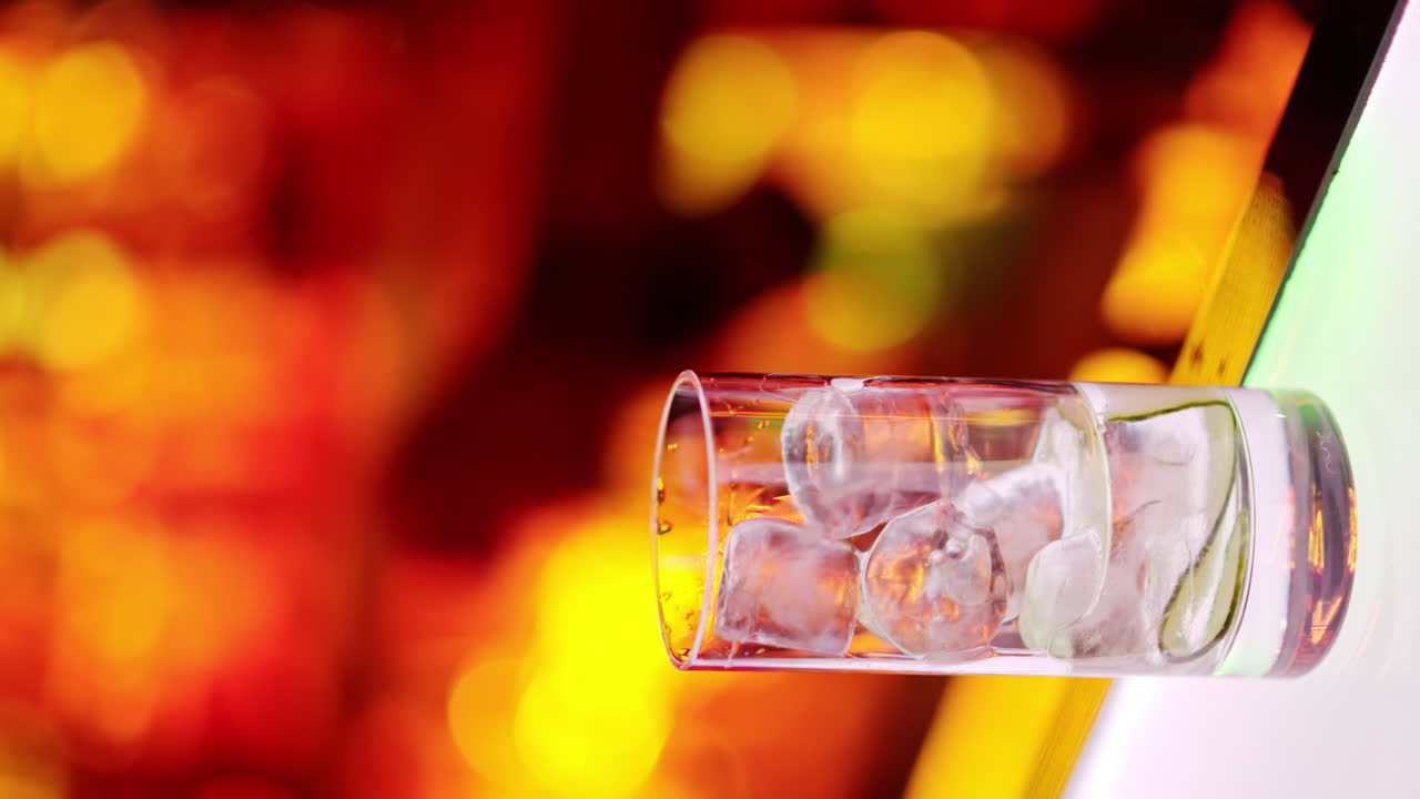 Barman making cocktails with whiskey liquor alcohol at the bar at night with red neon lights, slow motion vertical screen