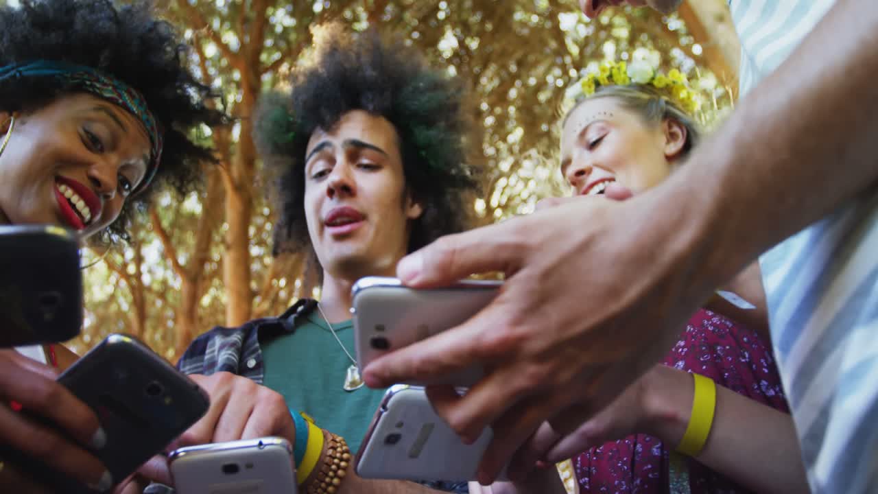 amigos interactuando y usando teléfonos móviles en el parque 4k