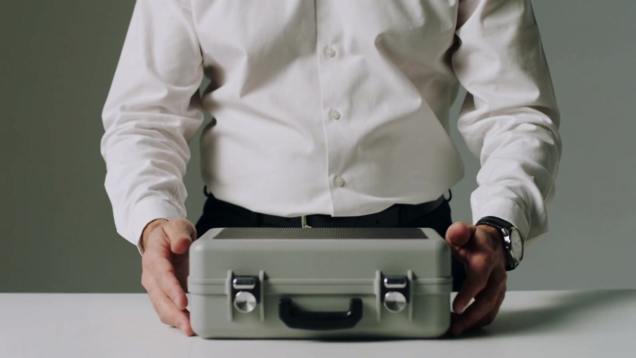 Fastening black smartwatch man in white shirt grasping metal briefcase in studio preparing
