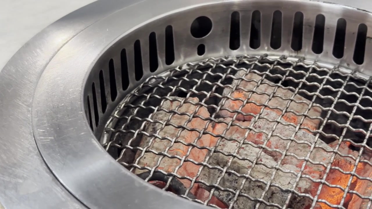 Nærbilde av en tom grill med glødende kullglør, stigende varme og røykfylt atmosfære, klar for utendørs grilling og matlaging