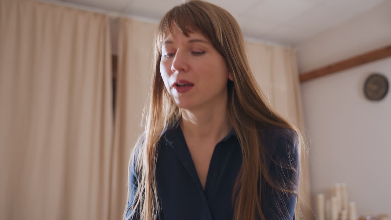 Professional walking to seat on sofa observing patient working with soft soil mold on tray during therapy session focused on tactile mindfulness and emotional healing in cozy counseling room