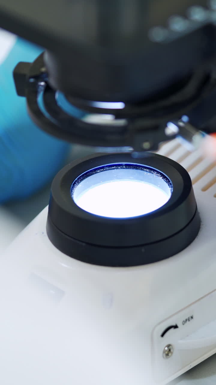 Chemist examining blood with microscope. Close up shot of scientific laboratory microscope examining blood. Vertical video