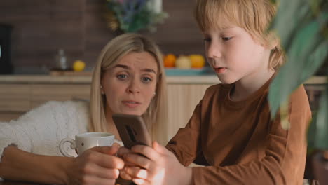 niño pequeño y madre viendo el teléfono inteligente y usando una aplicación en casa
