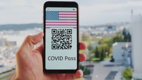 male hand holds smartphone with covid pass on screen macro