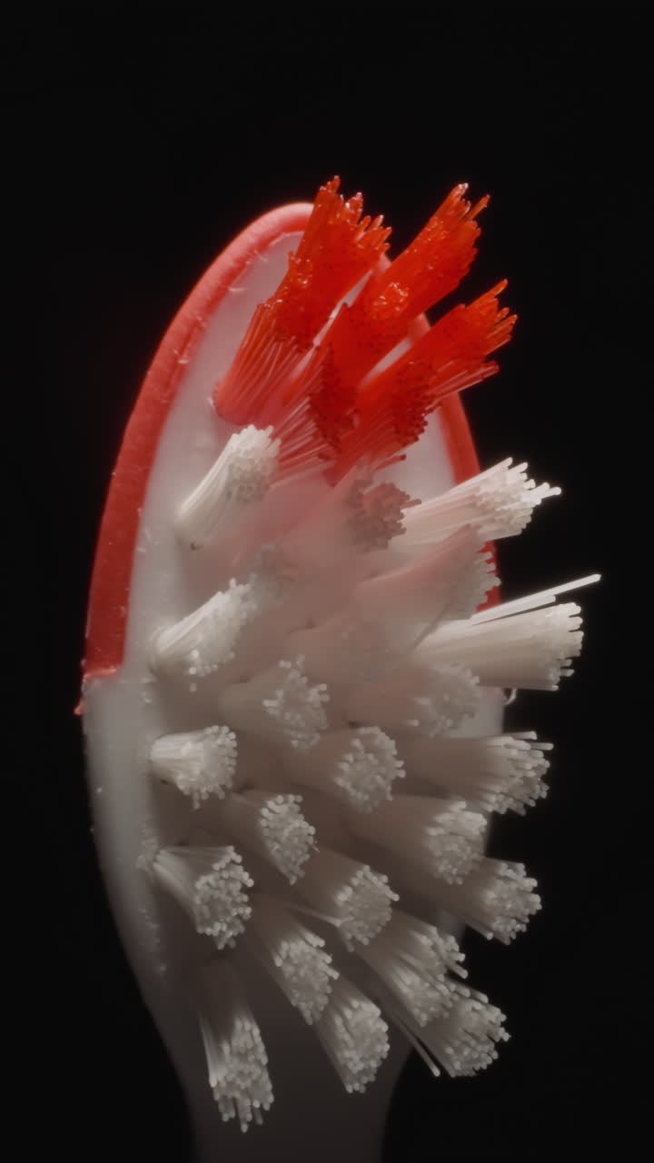 Children toothbrush with hard bristles on black background. Small red and white brush used for cleaning kids teeth. Morning routine concept macro