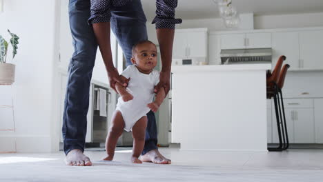 close up of father encouraging smiling baby son to take first steps and walk at home