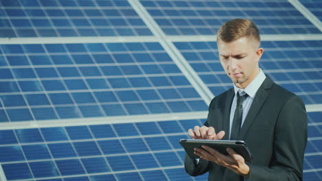 a young businessman uses a tablet near a solar power station