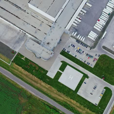 factory on green field. view from above on industrial territory and many cars nearby. white trucks on the parking zone. aerial view.