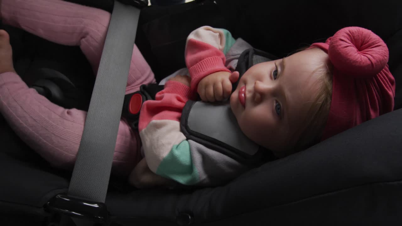 Caucasian mother kissing her baby in safety seat in the car