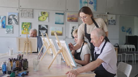 like senior friends attending together at a painting class. small group taking a variety of fun classes together. a group of elderly people attend a master class on drawing together spending time.