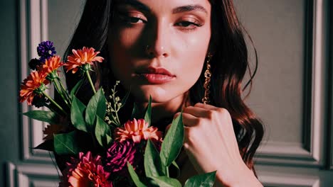 glamorous fashion model holding vibrant floral bouquet during stylized studio photoshoot, displaying elegant portrait with changing light and artistic image filters
