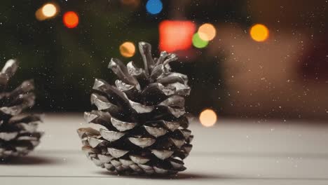 Animation-of-snow-falling-over-close-up-of-pine-cones