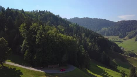 A-red-Ford-Focus-RS-drives-out-of-a-forest-into-a-beautiful-open-mountain-scenery