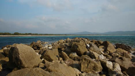 Ascending-shot-over-breakwater-rocks-on-the-coast-of-Sardinia-on-a-sunny-day