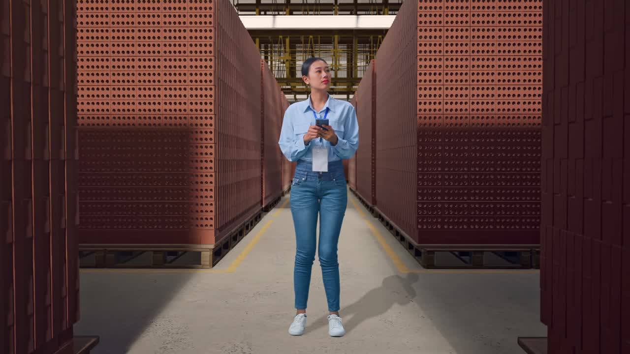 Full Body Of Asian Female Worker With Her Smarphone With Red Brick Packed in Stacks Are Stored, She Observes By Looking Around Before She Come To Concentrating With Her Smarphone