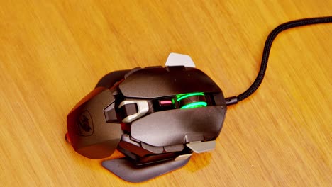 Gamer-mouse-with-rainbow-LED-lights,-hand-coming-into-screen-double-clicking-and-exiting-screen