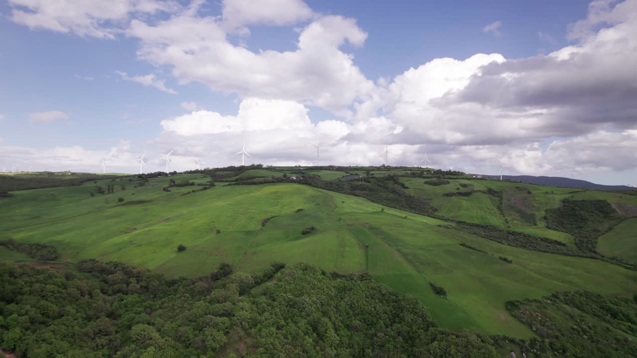 Aerial landscape of green hill with windmill on top at horizon generate renewable energy