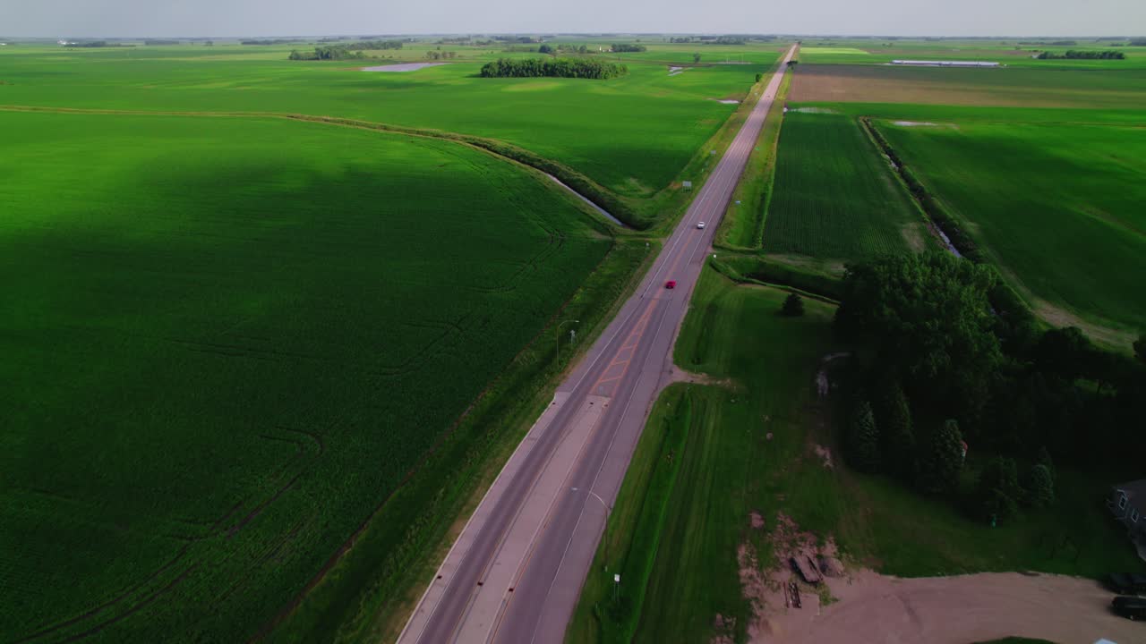 Aerial view of a rural roundabout with a school bus parked near farm buildings in the countryside.