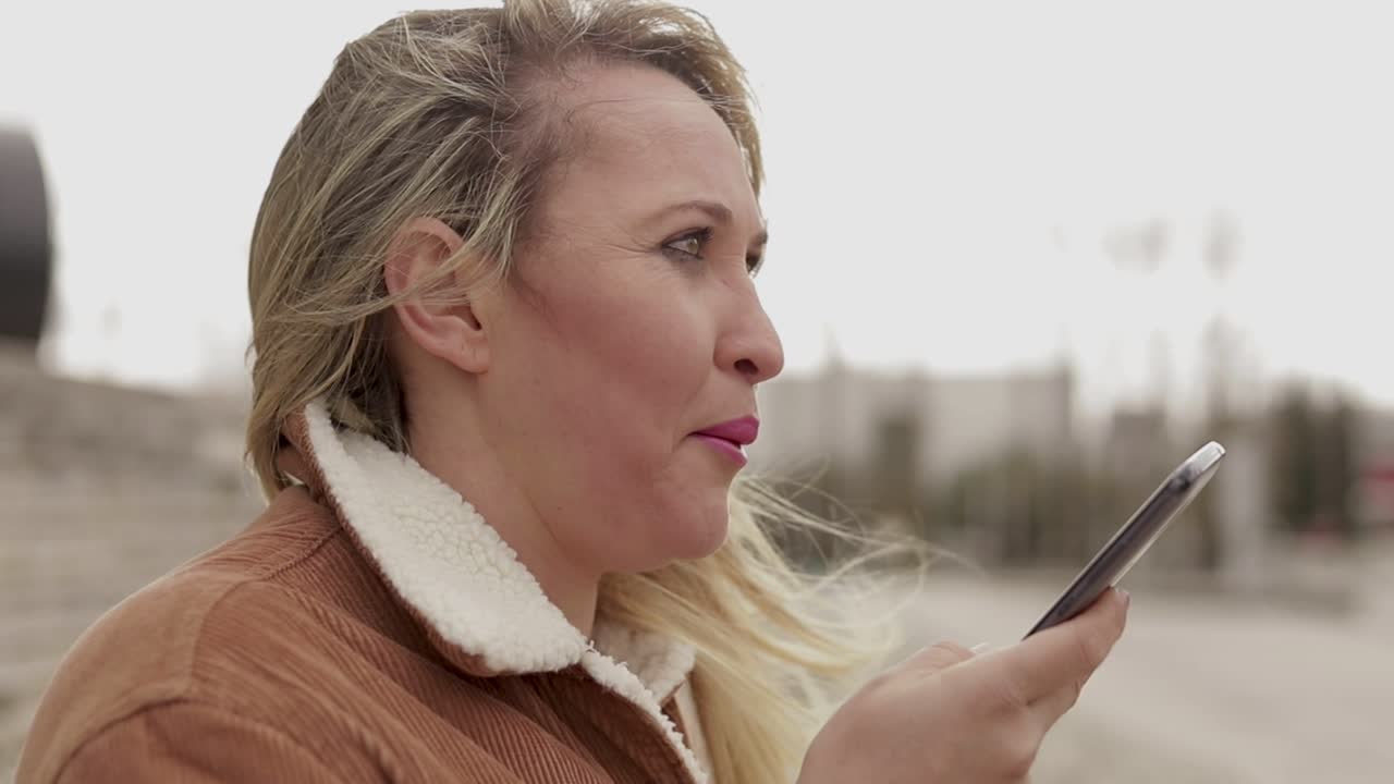 Mature woman wearing warm clothing talking on smartphone outdoor