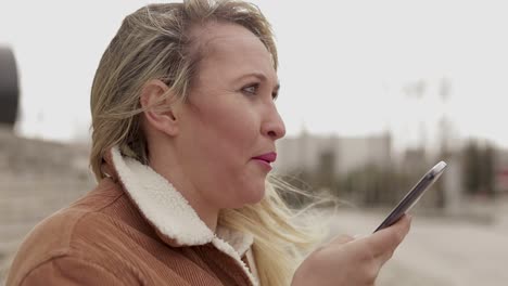 mature woman wearing warm clothing talking on smartphone outdoor