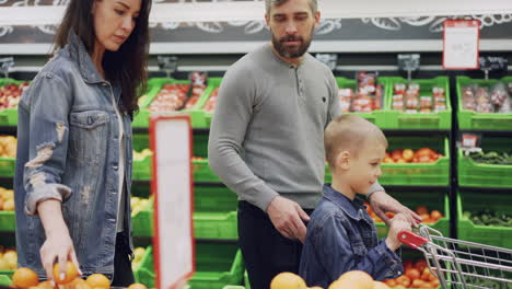 family shopping for oranges at the grocery store